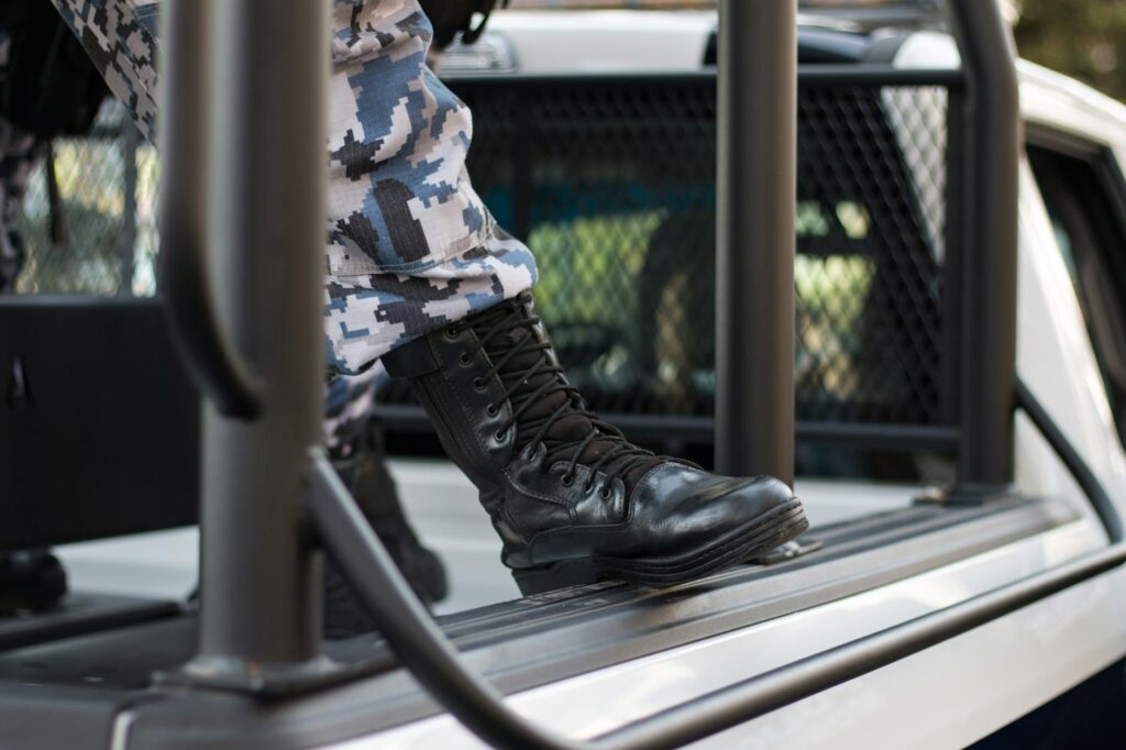 Close-up shot of black boots in camouflage uniform stepping on a police vehicle in Xalapa-Enríquez, Mexico.